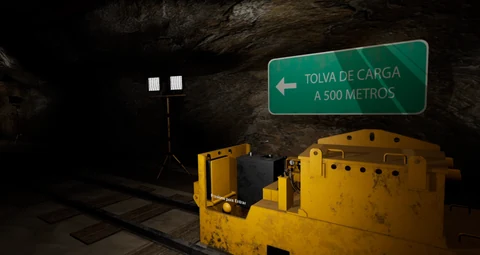 A yellow mine locomotive beneath a loading-hopper direction sign in an underground tunnel.
