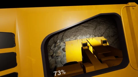 View from a yellow scoop cab over its bucket toward a pile of rocks.